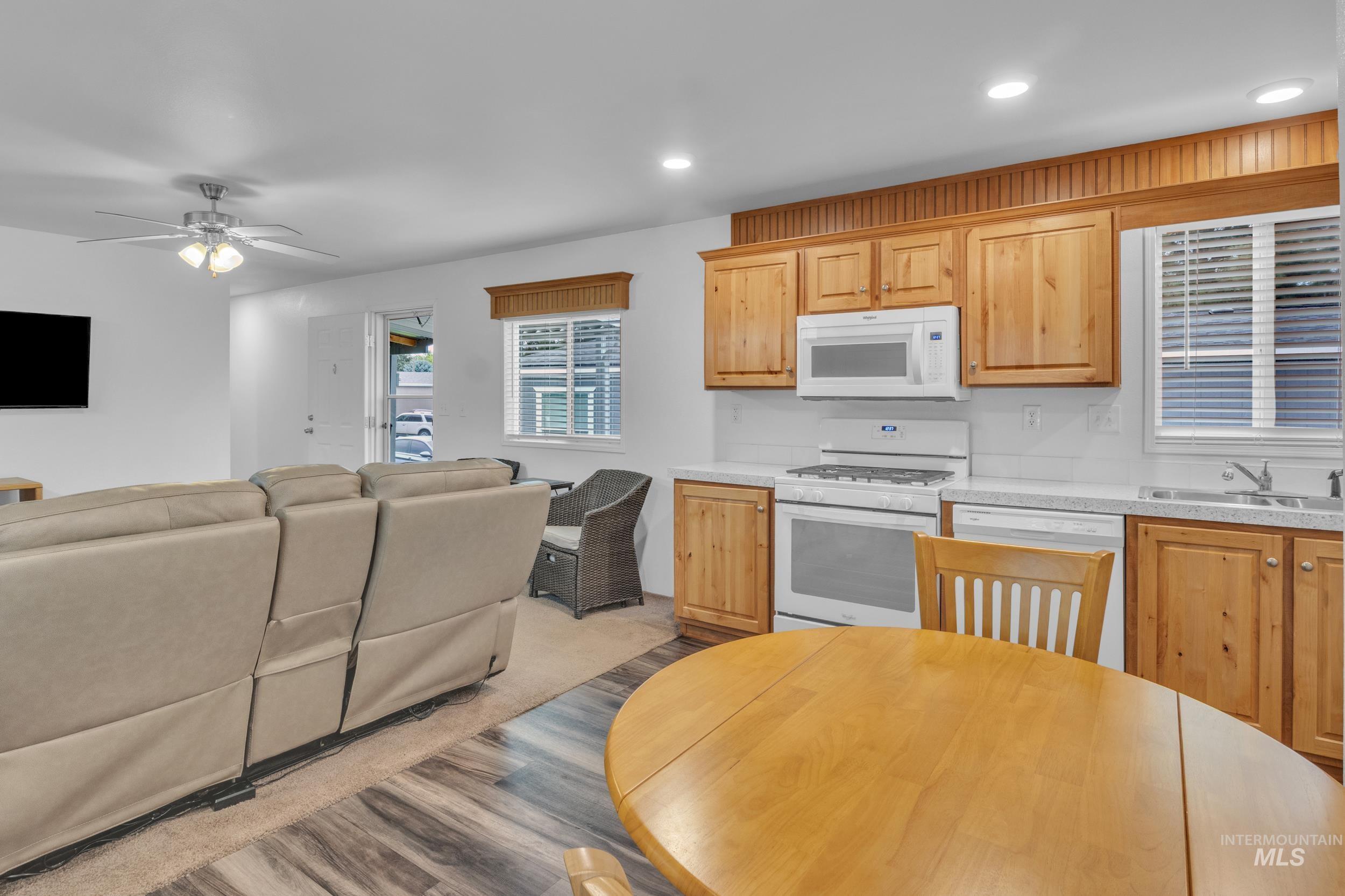 Kitchen featuring white appliances, light countertops, open floor plan, ceiling fan, and recessed lighting