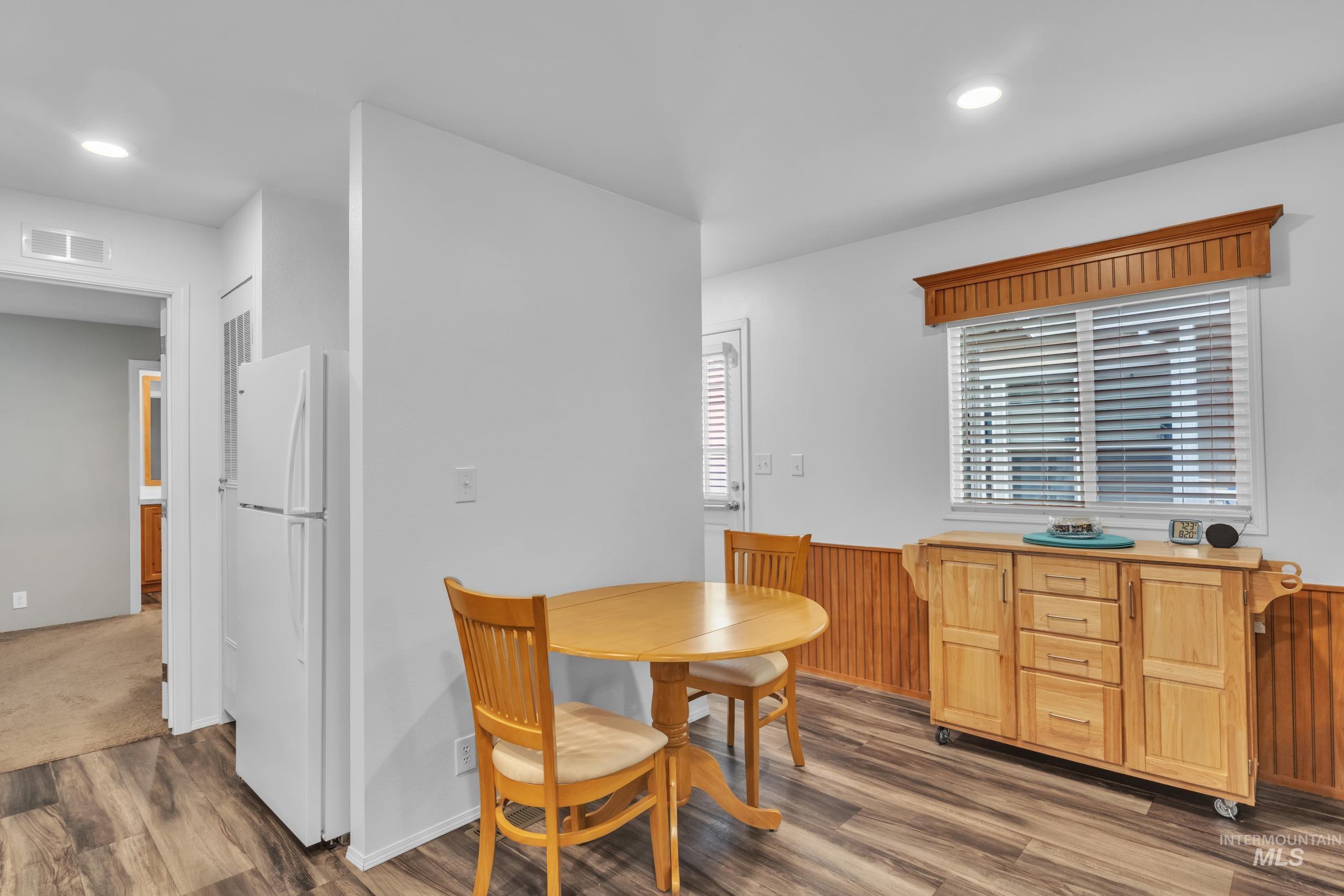 Dining area with dark wood-style flooring, wainscoting, wood walls, and recessed lighting