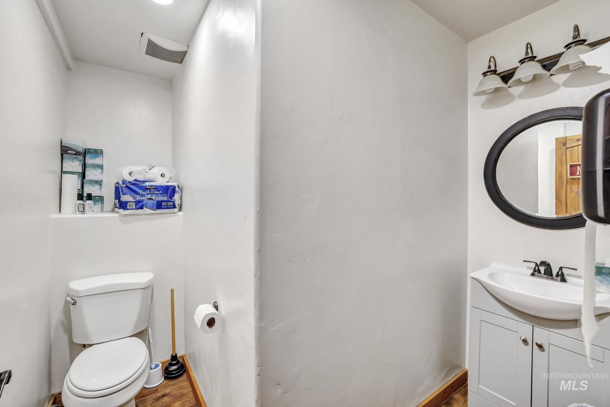 Half bath with vanity and dark wood-type flooring