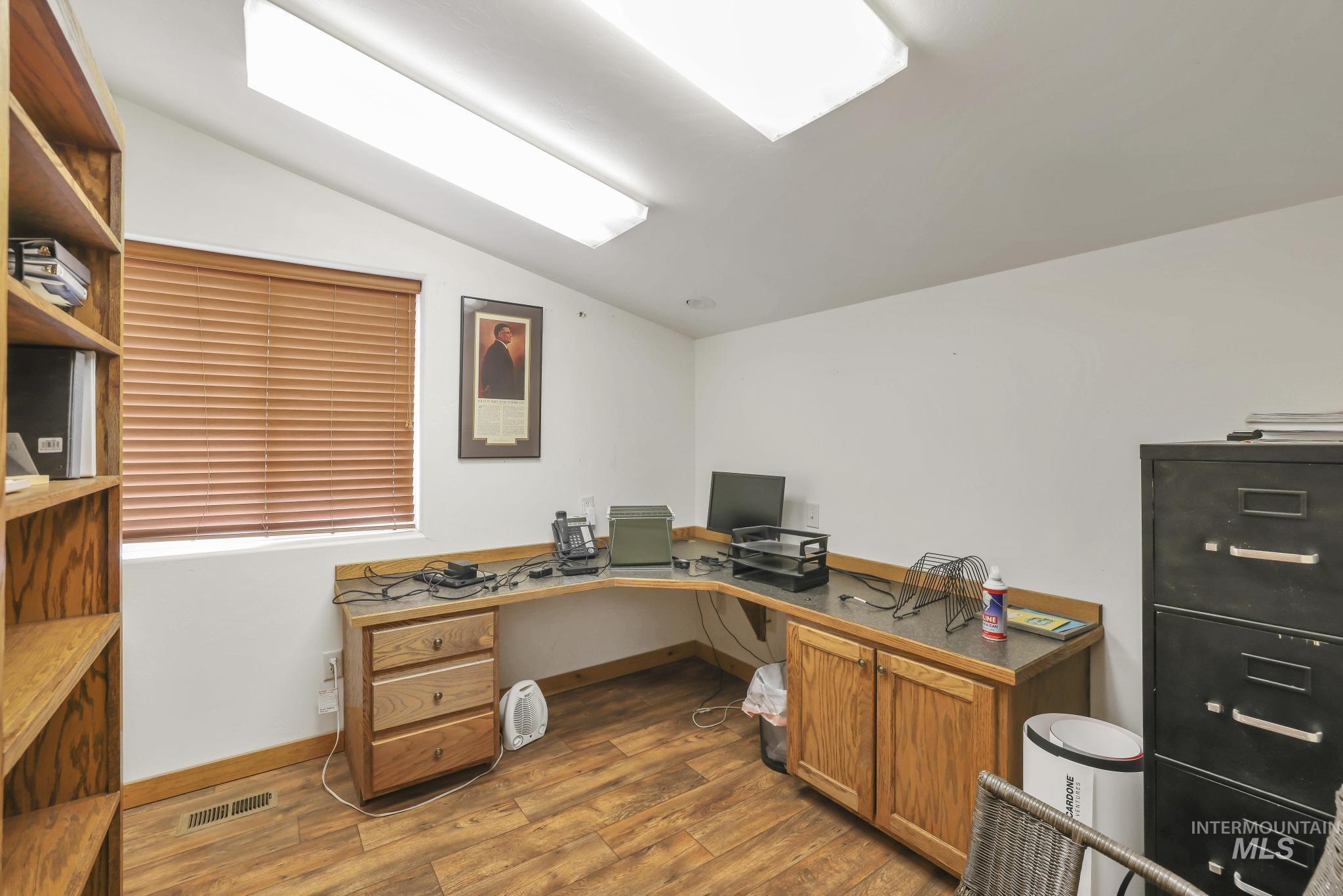 Office space featuring vaulted ceiling, dark wood-type flooring, and built in desk