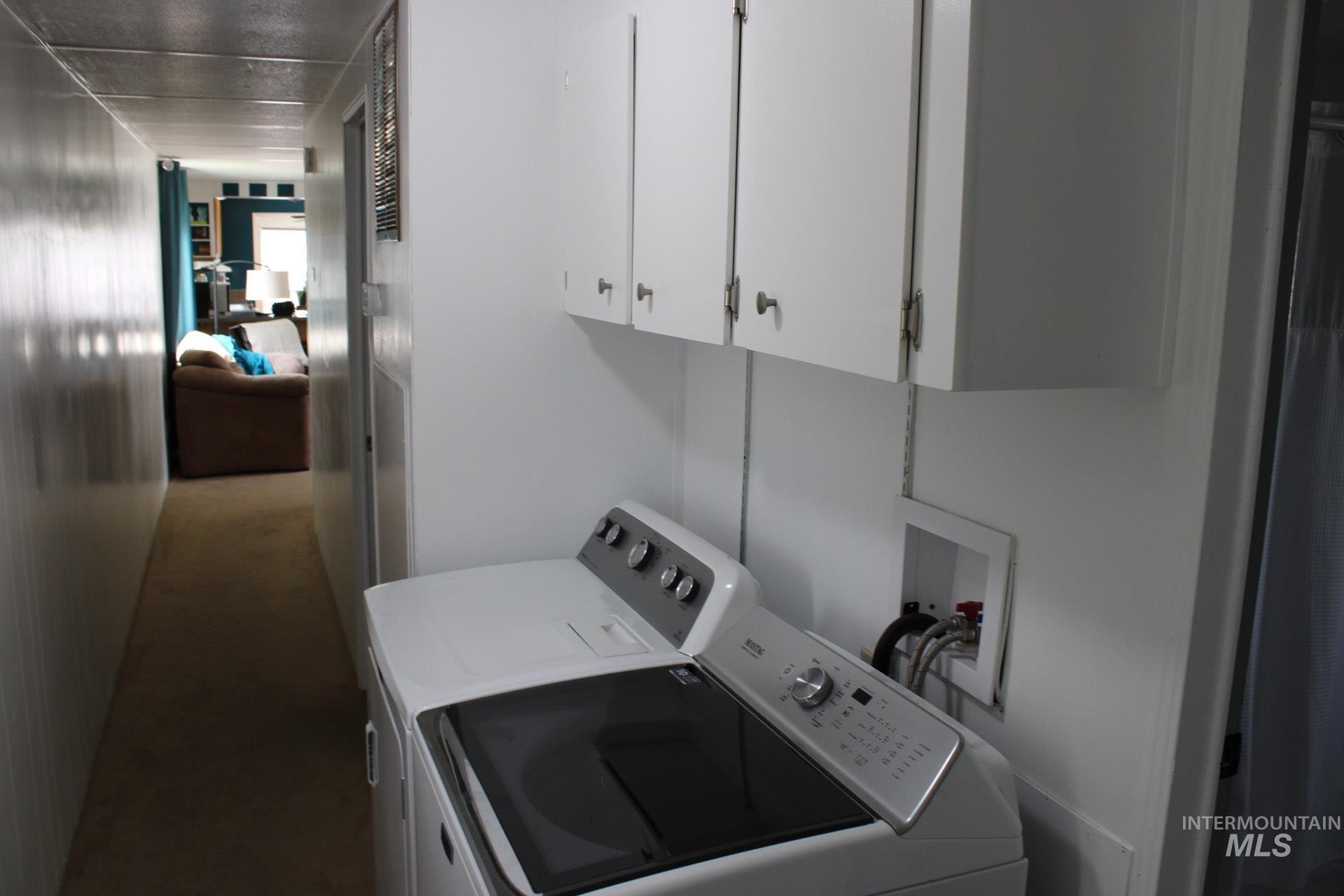 Washroom with cabinet space and washing machine and clothes dryer