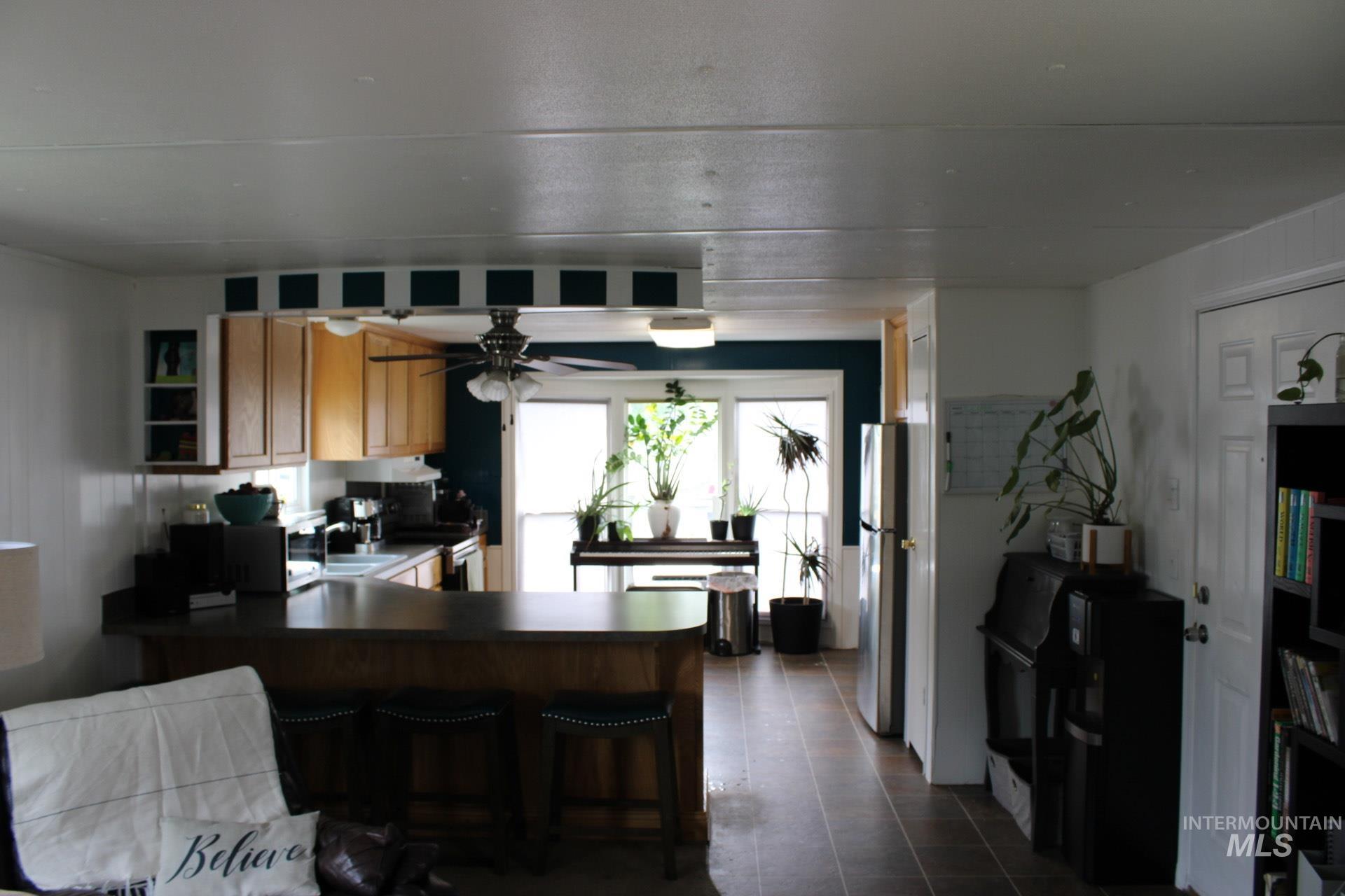 Kitchen with a kitchen bar, dark countertops, a peninsula, stainless steel appliances, and ceiling fan