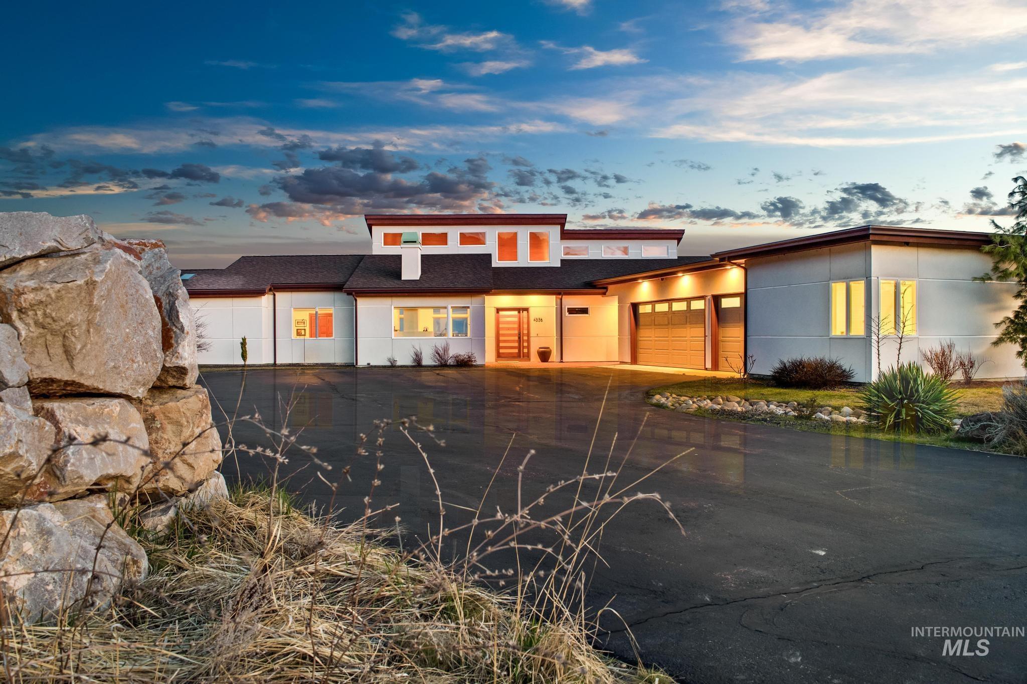 View of front facade featuring a garage, driveway, and a shingled roof