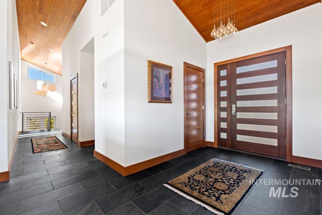 Entryway featuring wood ceiling, high vaulted ceiling, and a chandelier