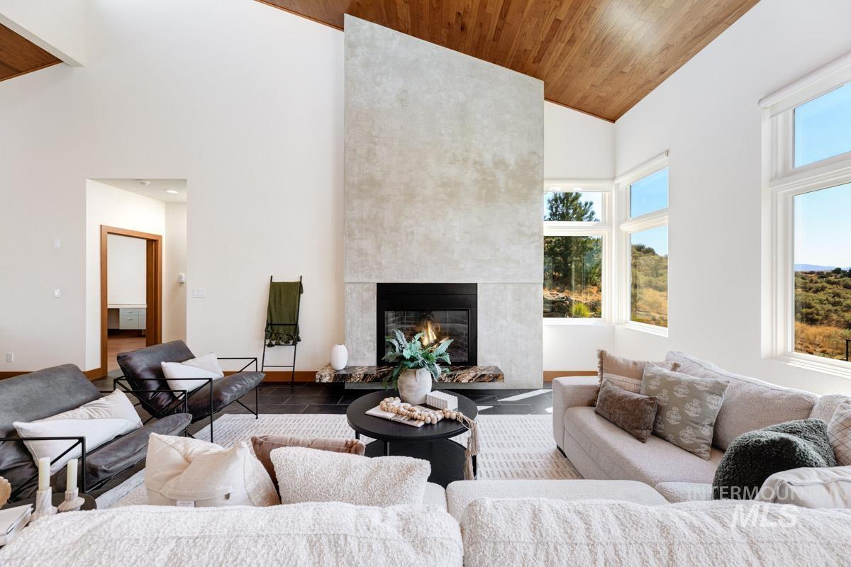 Living area featuring high vaulted ceiling, a large fireplace, and wooden ceiling