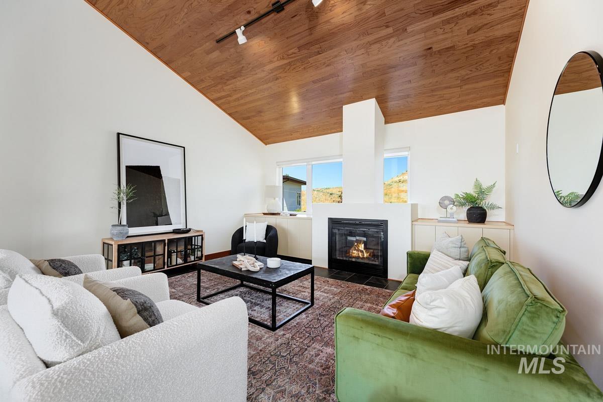 Living room with track lighting, a fireplace with flush hearth, wooden ceiling, and high vaulted ceiling