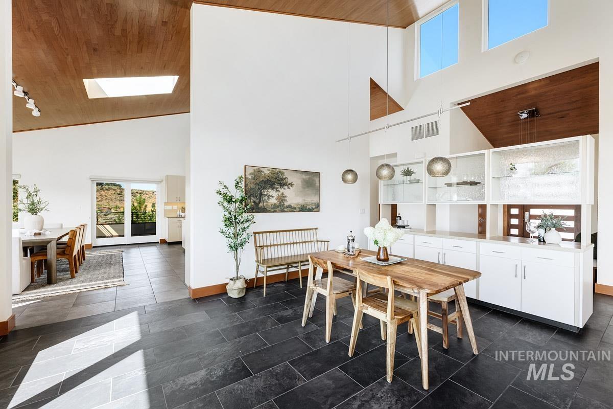 Dining area with high vaulted ceiling, wood ceiling, and a skylight