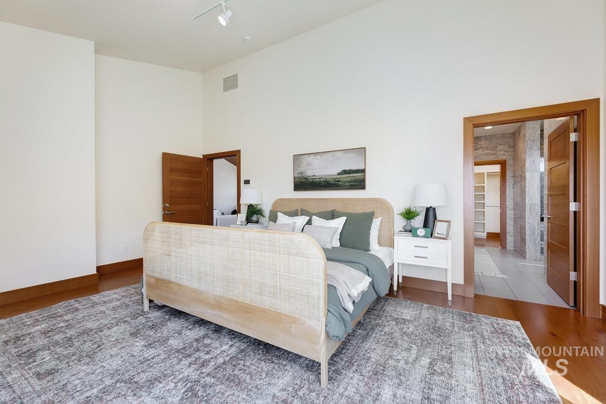 Bedroom featuring a towering ceiling, wood finished floors, and a ceiling fan