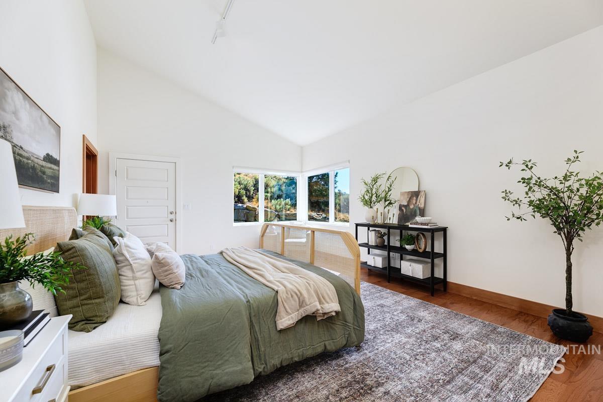 Bedroom with wood finished floors and high vaulted ceiling