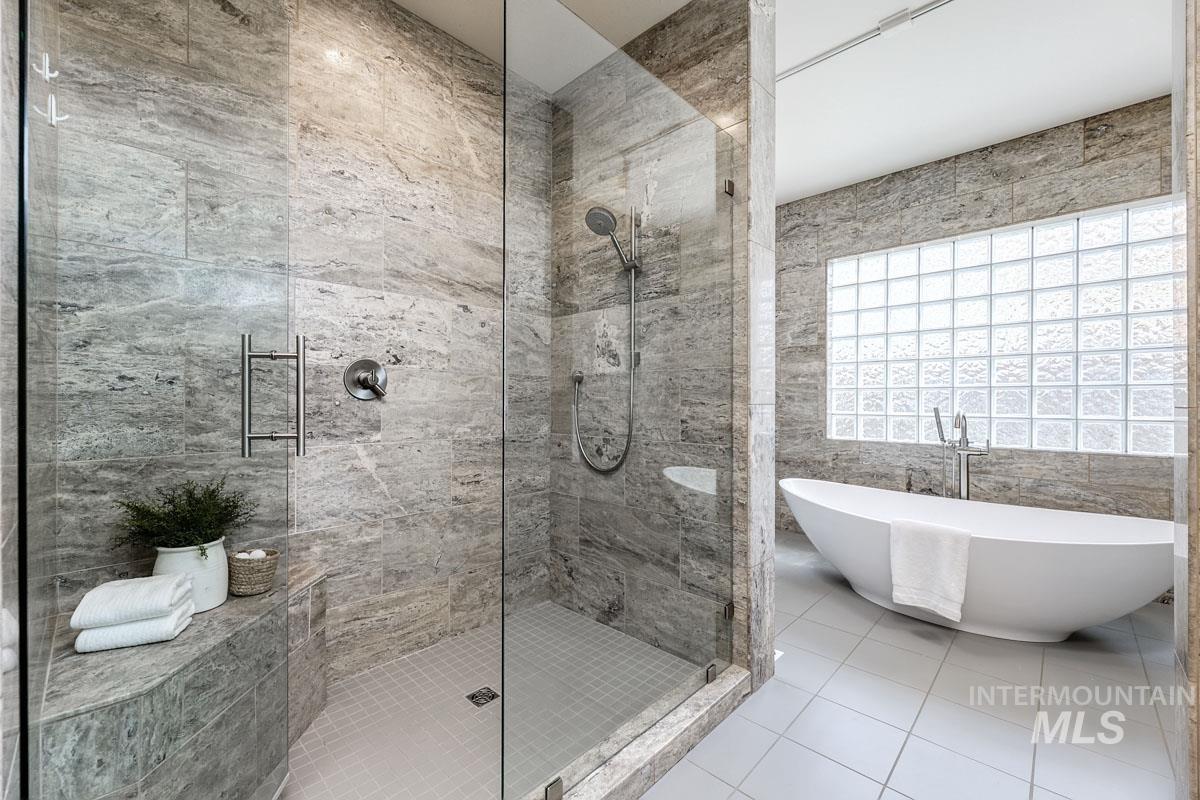Full bathroom featuring tile walls, a shower stall, tile patterned floors, and a soaking tub
