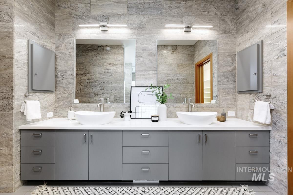 Full bathroom featuring double vanity, tile walls, and light tile patterned flooring