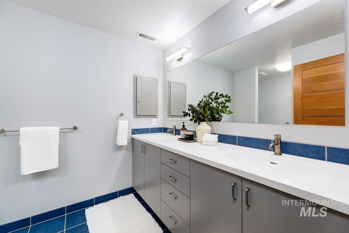 Bathroom featuring double vanity and dark tile patterned flooring