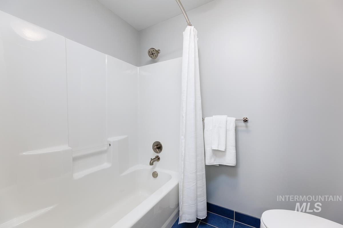 Bathroom featuring shower / tub combo with curtain and dark tile patterned floors