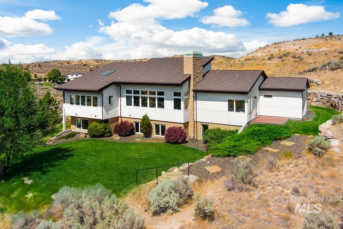 Back of property with a lawn, a chimney, stucco siding, and roof with shingles
