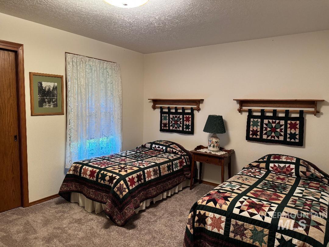 Carpeted bedroom with a textured ceiling and baseboards