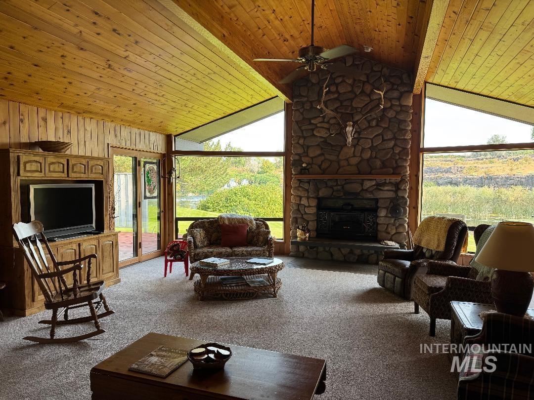 Living area with light carpet, wooden ceiling, a fireplace, lofted ceiling, and a ceiling fan