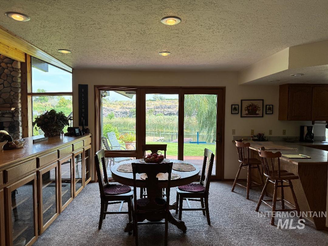 Dining space with light colored carpet and a textured ceiling