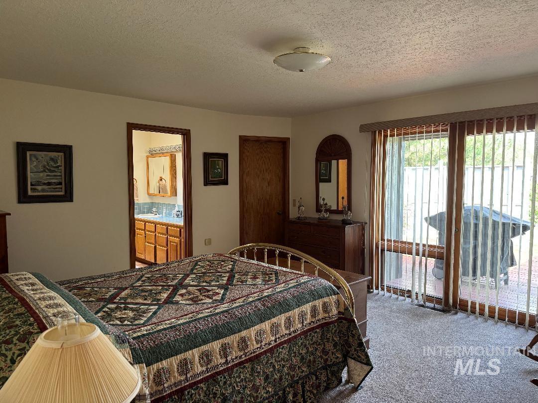 Carpeted bedroom with access to exterior and a textured ceiling