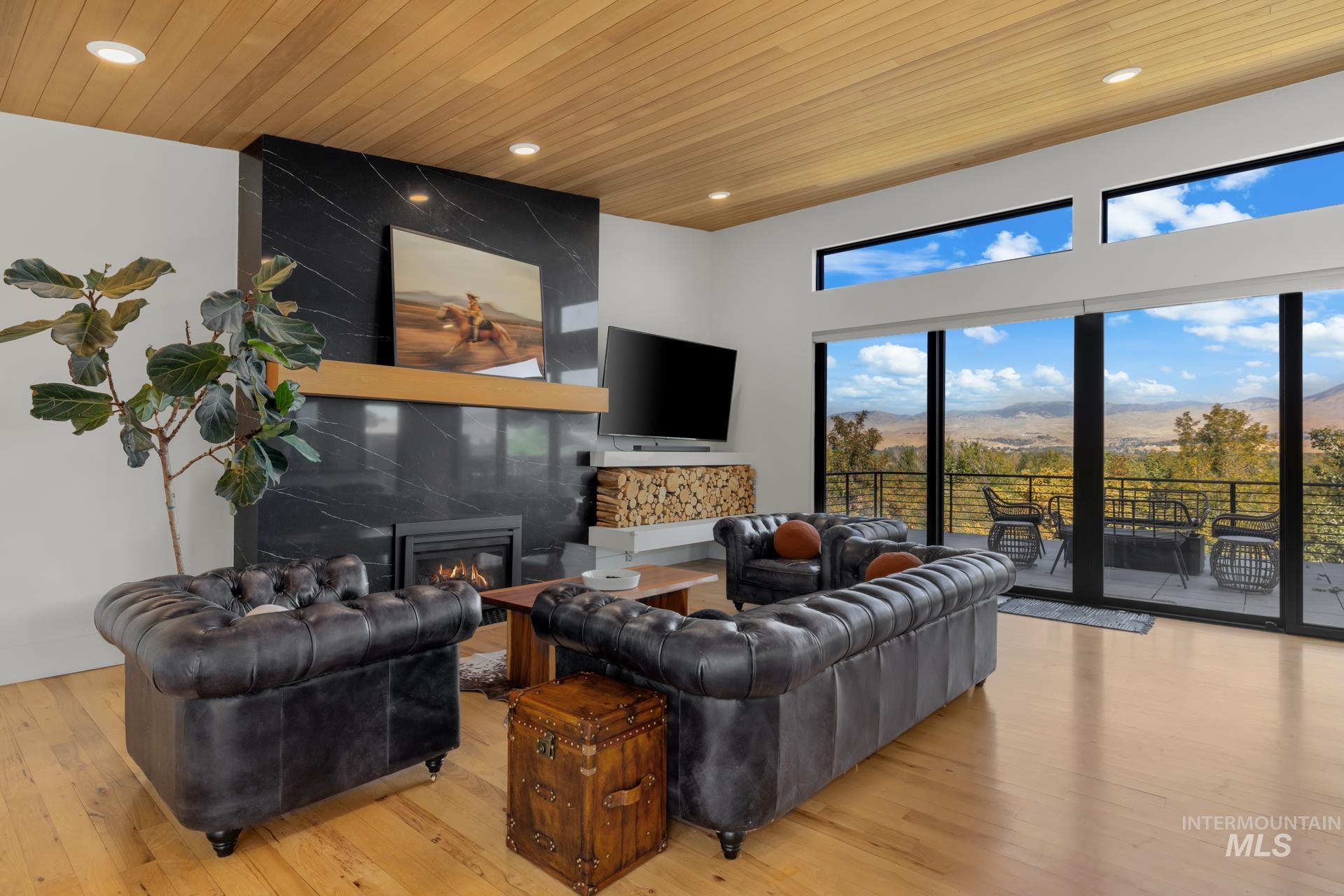 Living room featuring wooden ceiling, a high end fireplace, light wood-style floors, and recessed lighting