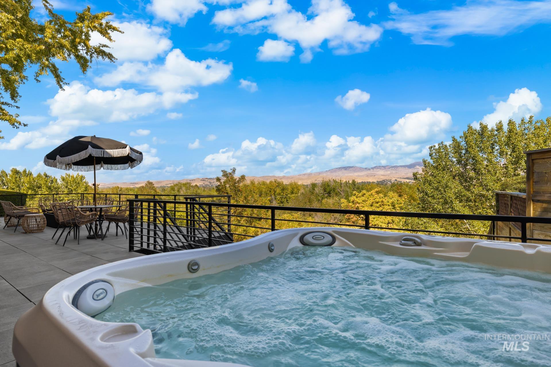 View of patio / terrace featuring a hot tub and a view of trees