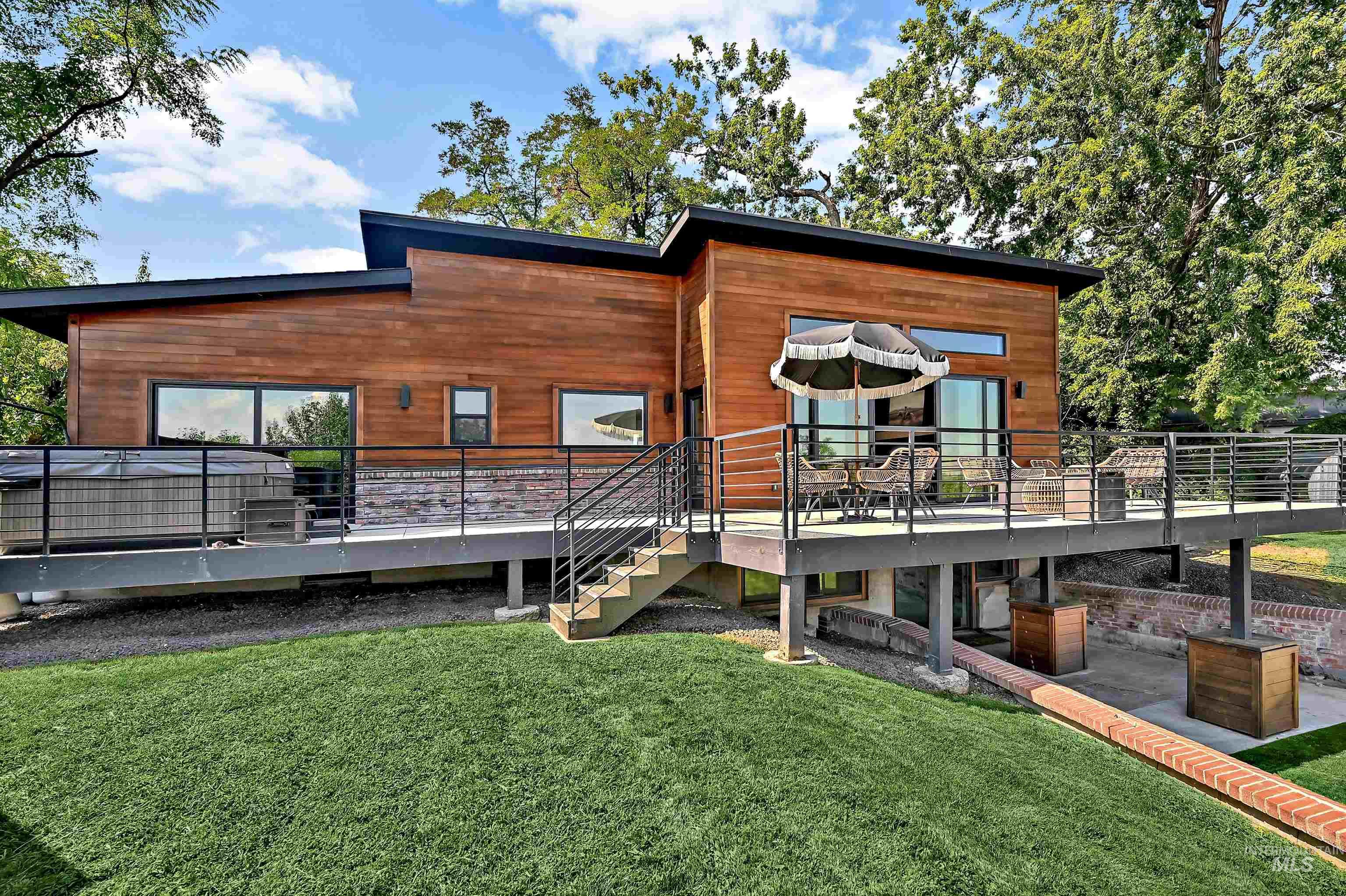 Back of property featuring a deck, a lawn, and stairs