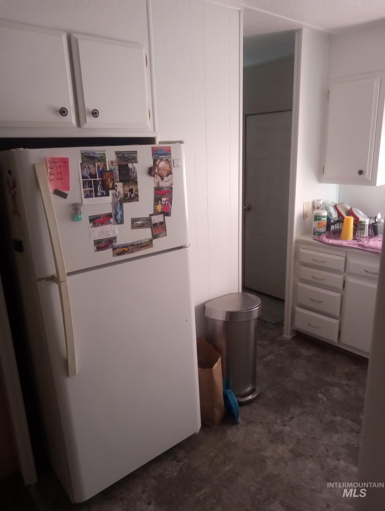 Kitchen with white cabinetry, freestanding refrigerator, and light countertops