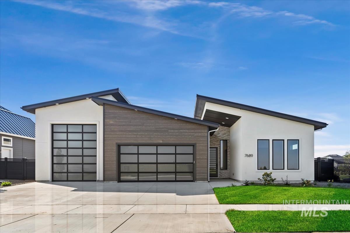 Contemporary home featuring a garage, stucco siding, and driveway