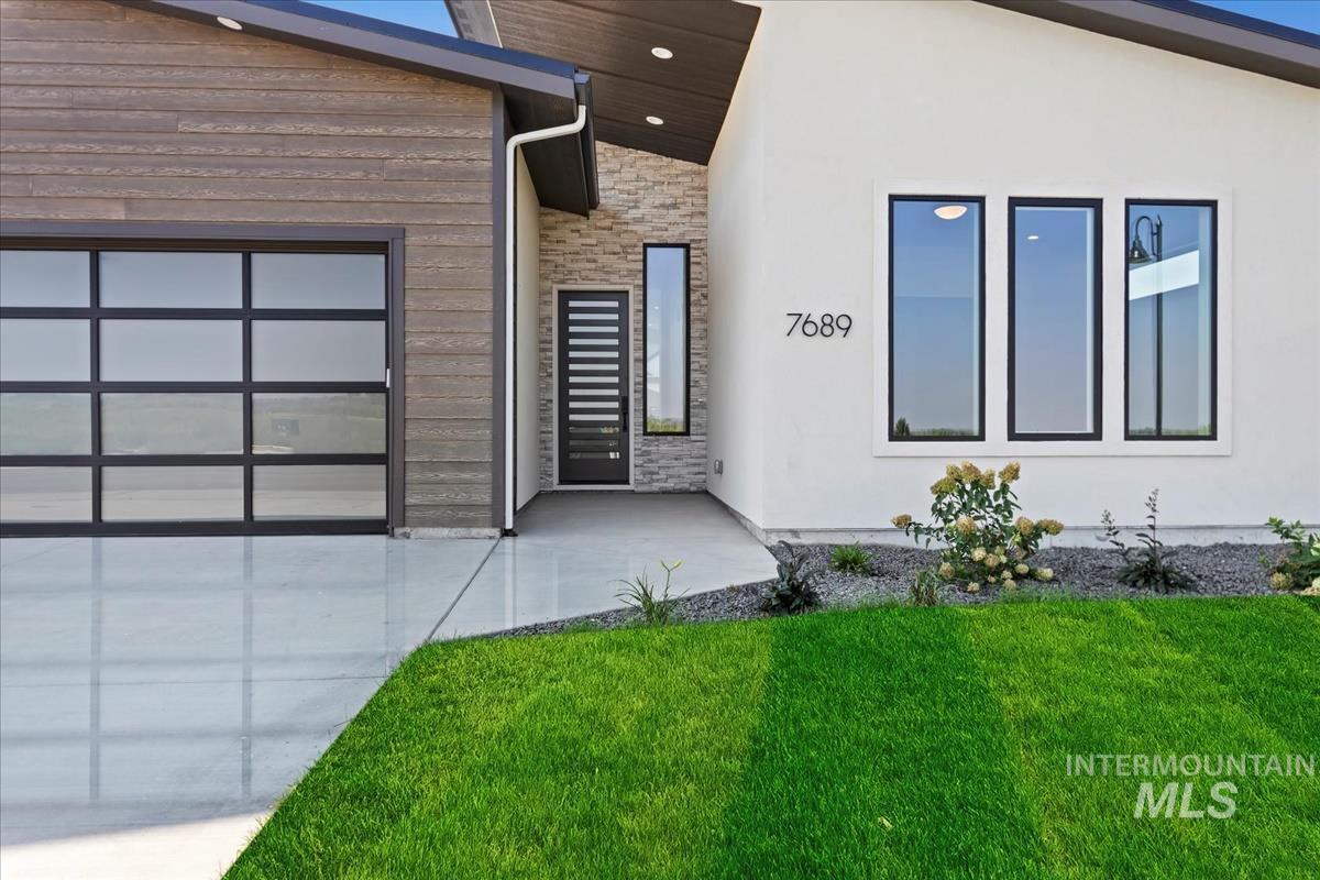 View of side of home with stone siding, a yard, and stucco siding