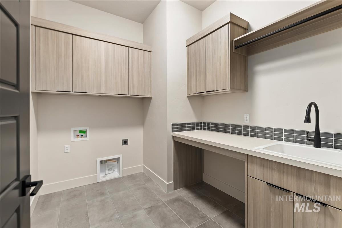 Laundry area with hookup for an electric dryer, washer hookup, light tile patterned flooring, and cabinet space