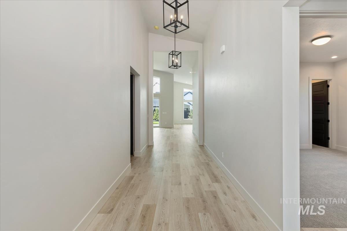 Corridor with light wood-style floors and a chandelier