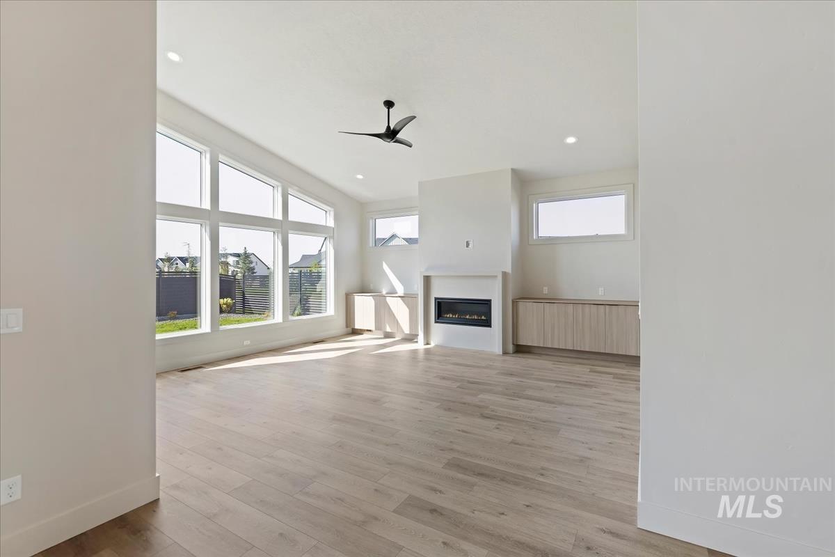 Unfurnished living room featuring a glass covered fireplace, light wood-style flooring, recessed lighting, and a ceiling fan