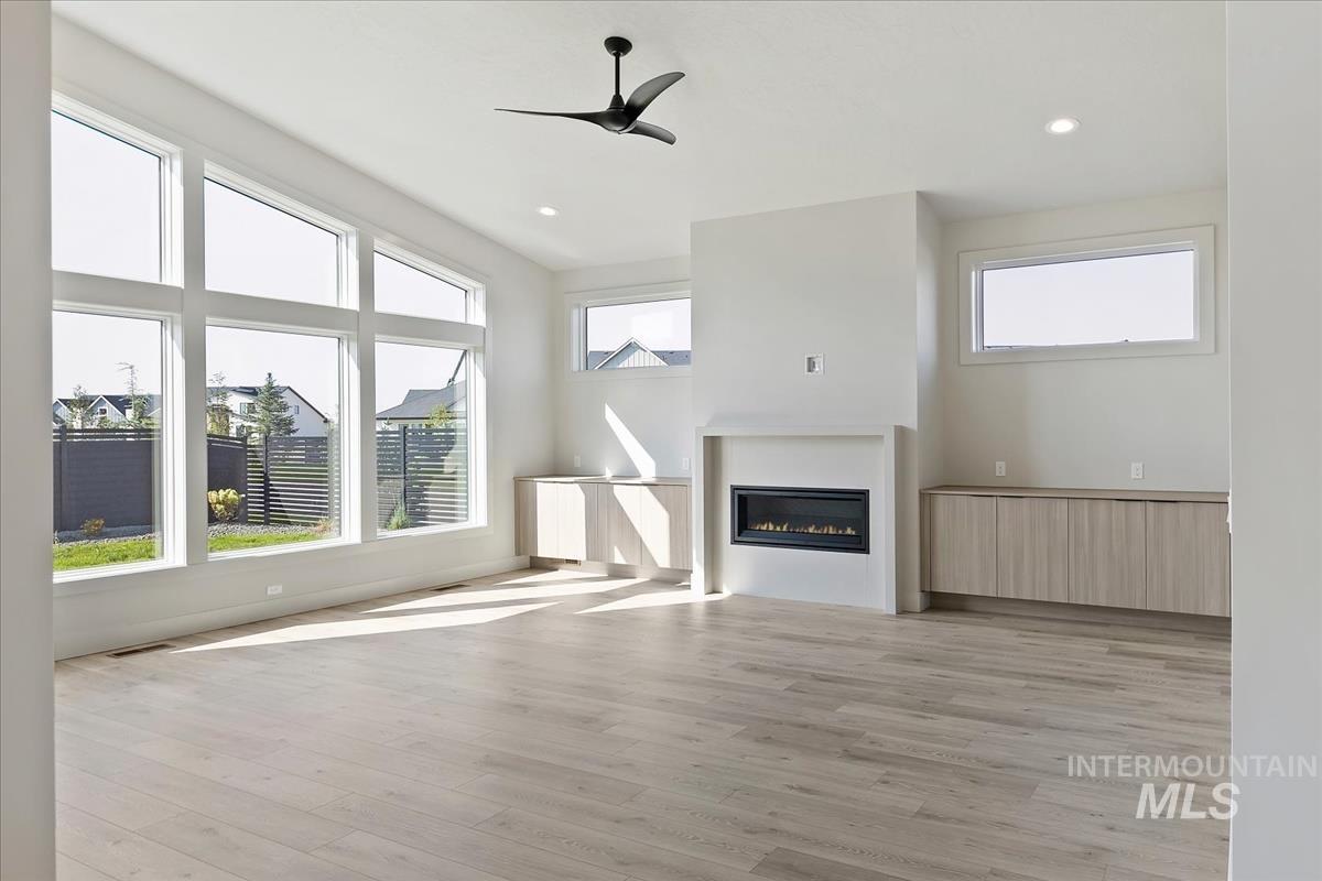 Unfurnished living room with a glass covered fireplace, light wood finished floors, a ceiling fan, and recessed lighting