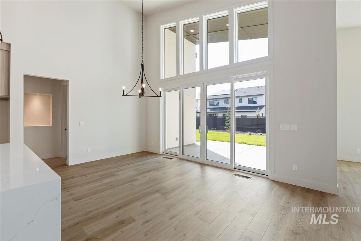 Unfurnished dining area featuring a chandelier, a high ceiling, and light wood-style flooring