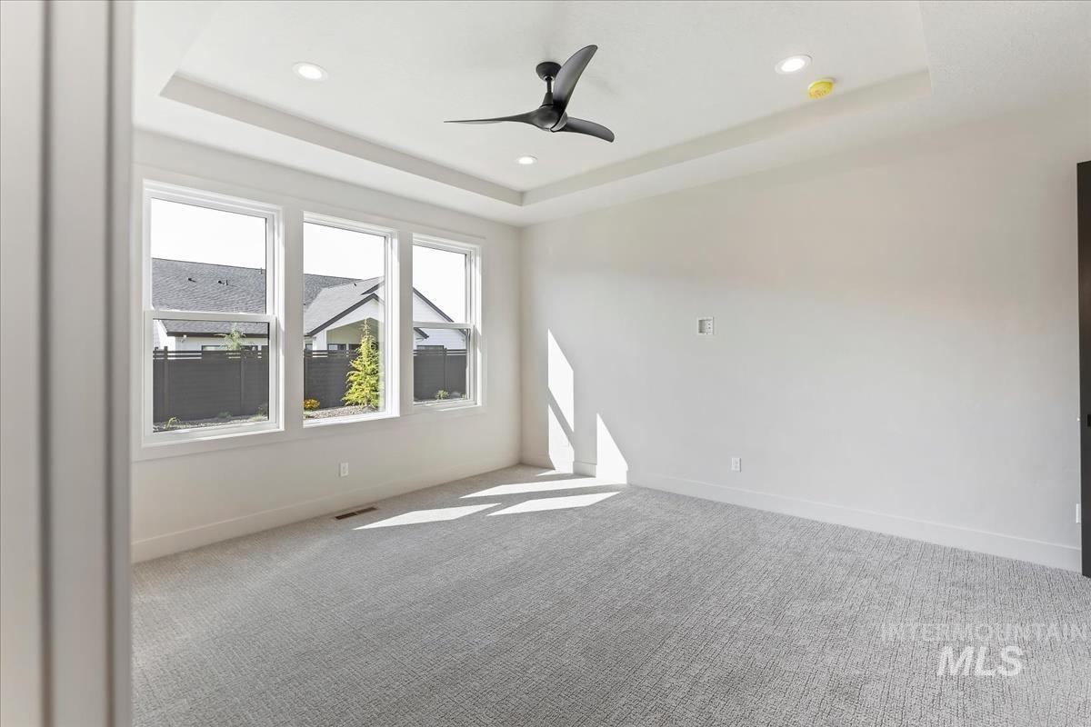 Unfurnished room with a tray ceiling, carpet floors, ceiling fan, and recessed lighting