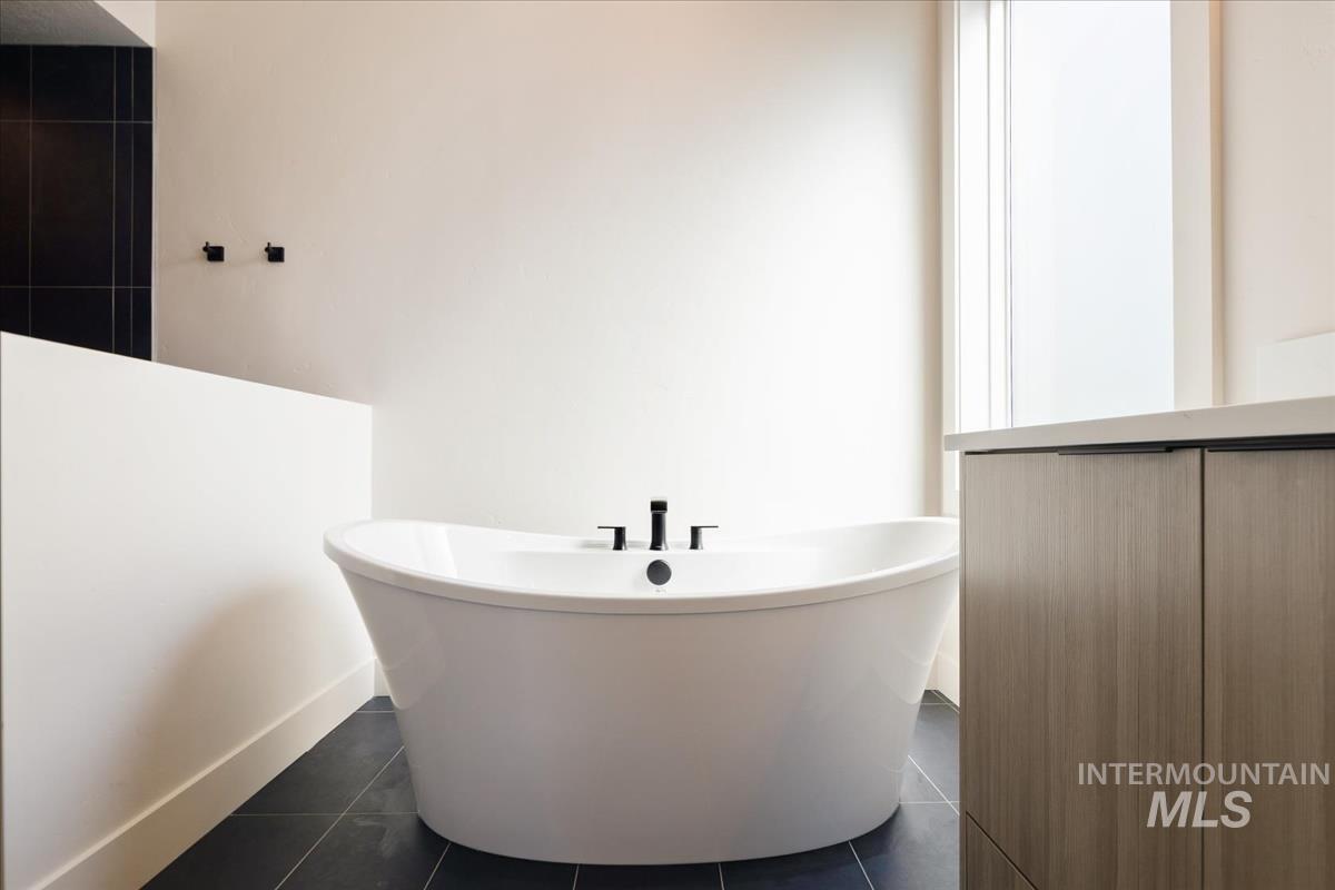 Bathroom with a freestanding tub and dark tile patterned floors