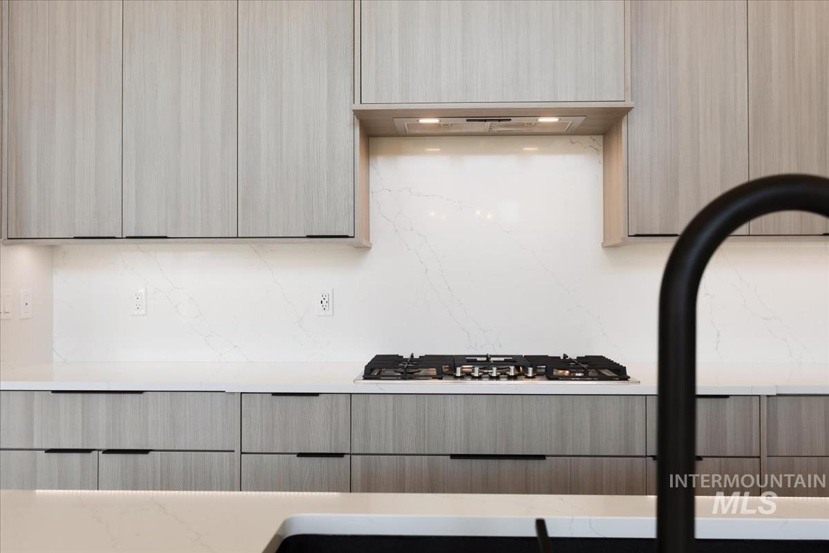 Kitchen with modern cabinets, light brown cabinets, light stone counters, and stainless steel gas stovetop