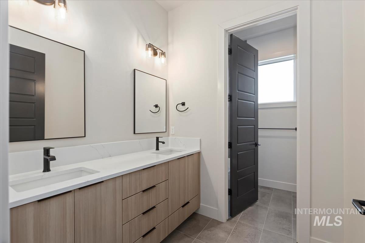 Full bathroom featuring double vanity, light tile patterned flooring, and a closet