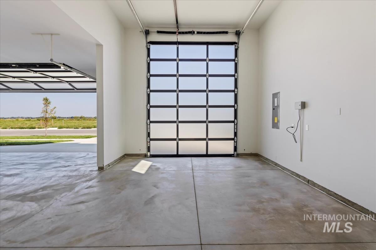 Garage with baseboards and electric panel