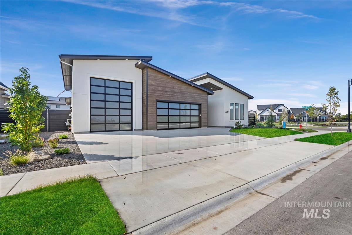 Contemporary home with driveway, stucco siding, an attached garage, and a residential view