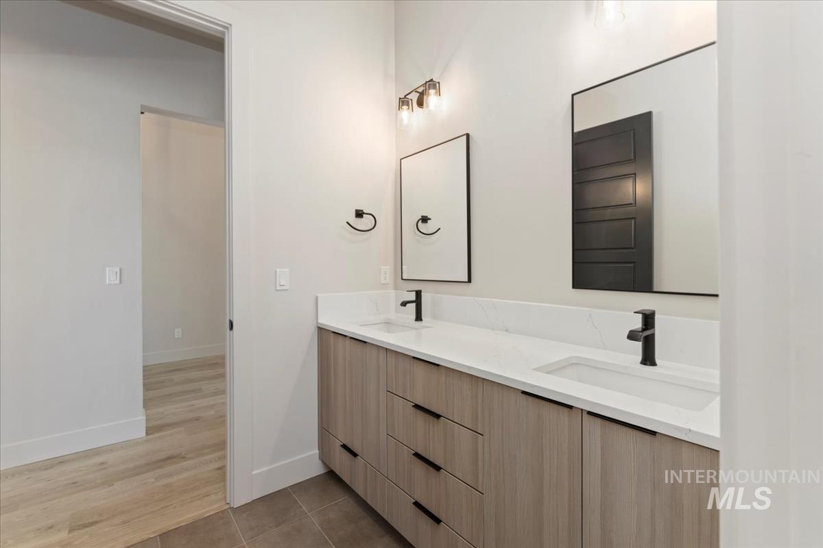 Full bath featuring double vanity and light tile patterned floors
