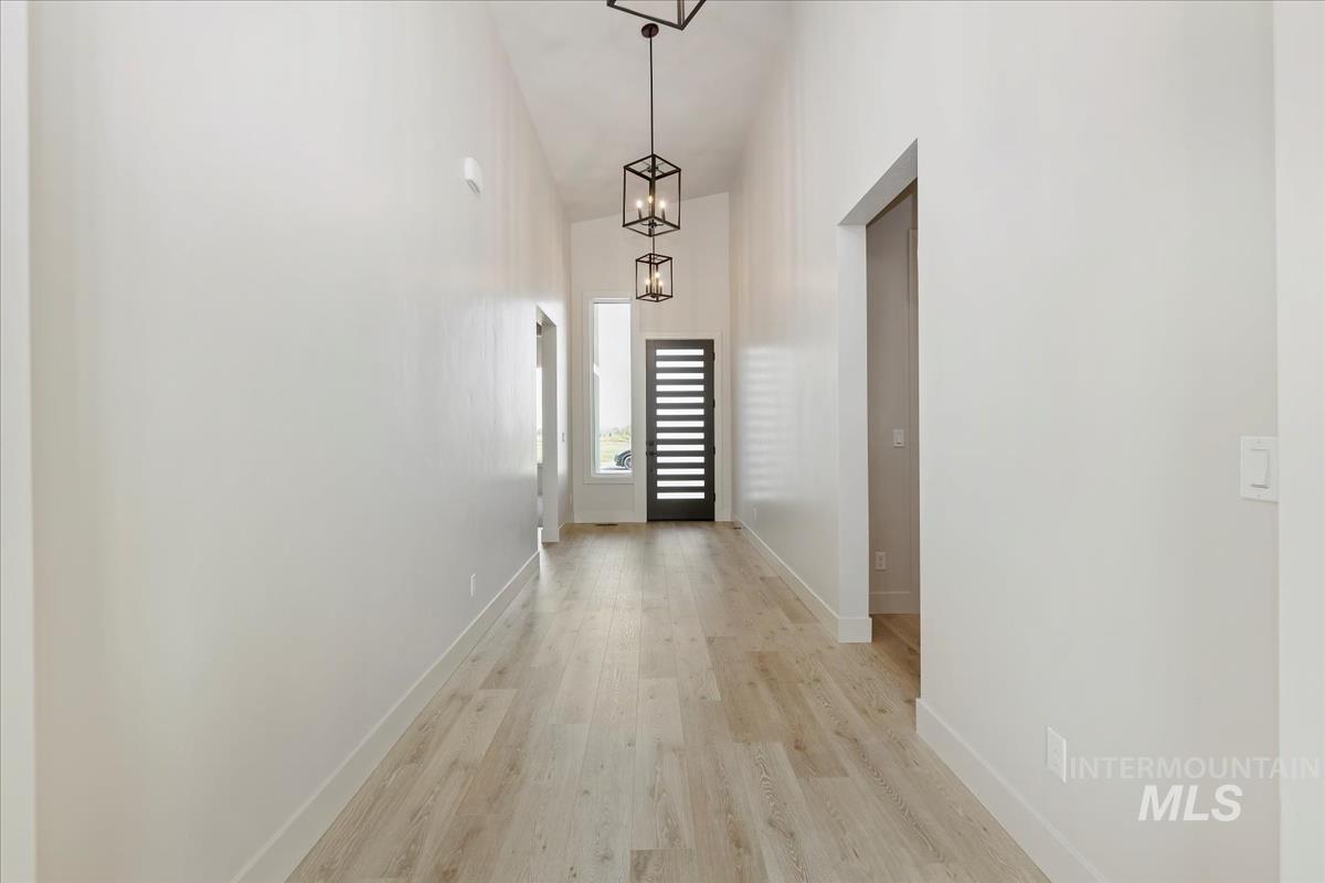 Corridor with light wood-style floors and high vaulted ceiling