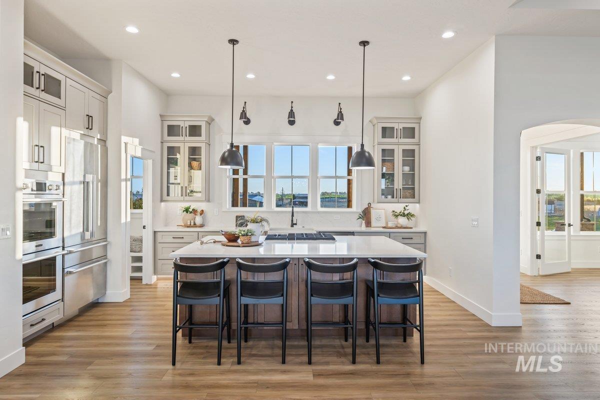 Kitchen with glass insert cabinets, a breakfast bar, a kitchen island with sink, arched walkways, and recessed lighting
