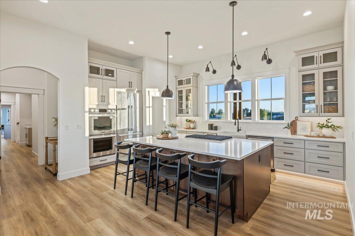 Kitchen featuring glass insert cabinets, a breakfast bar, a kitchen island, white cabinetry, and recessed lighting