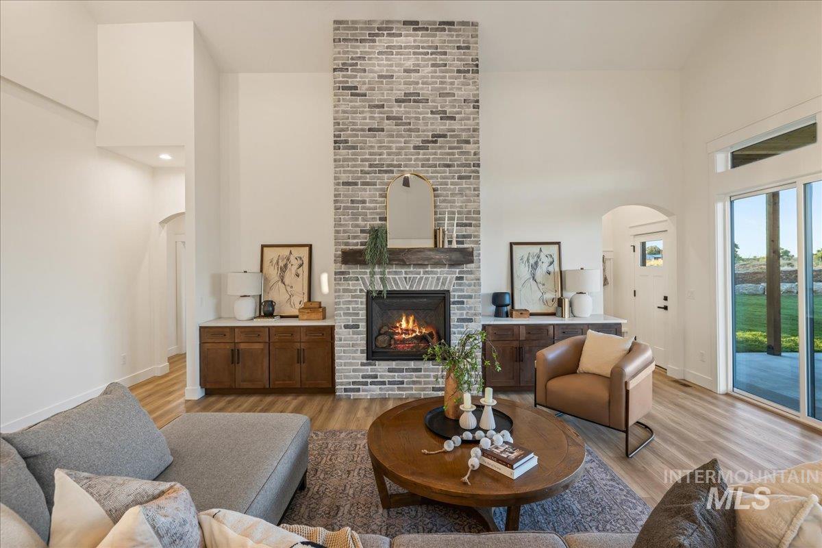 Living area featuring arched walkways, a towering ceiling, light wood-type flooring, and a fireplace