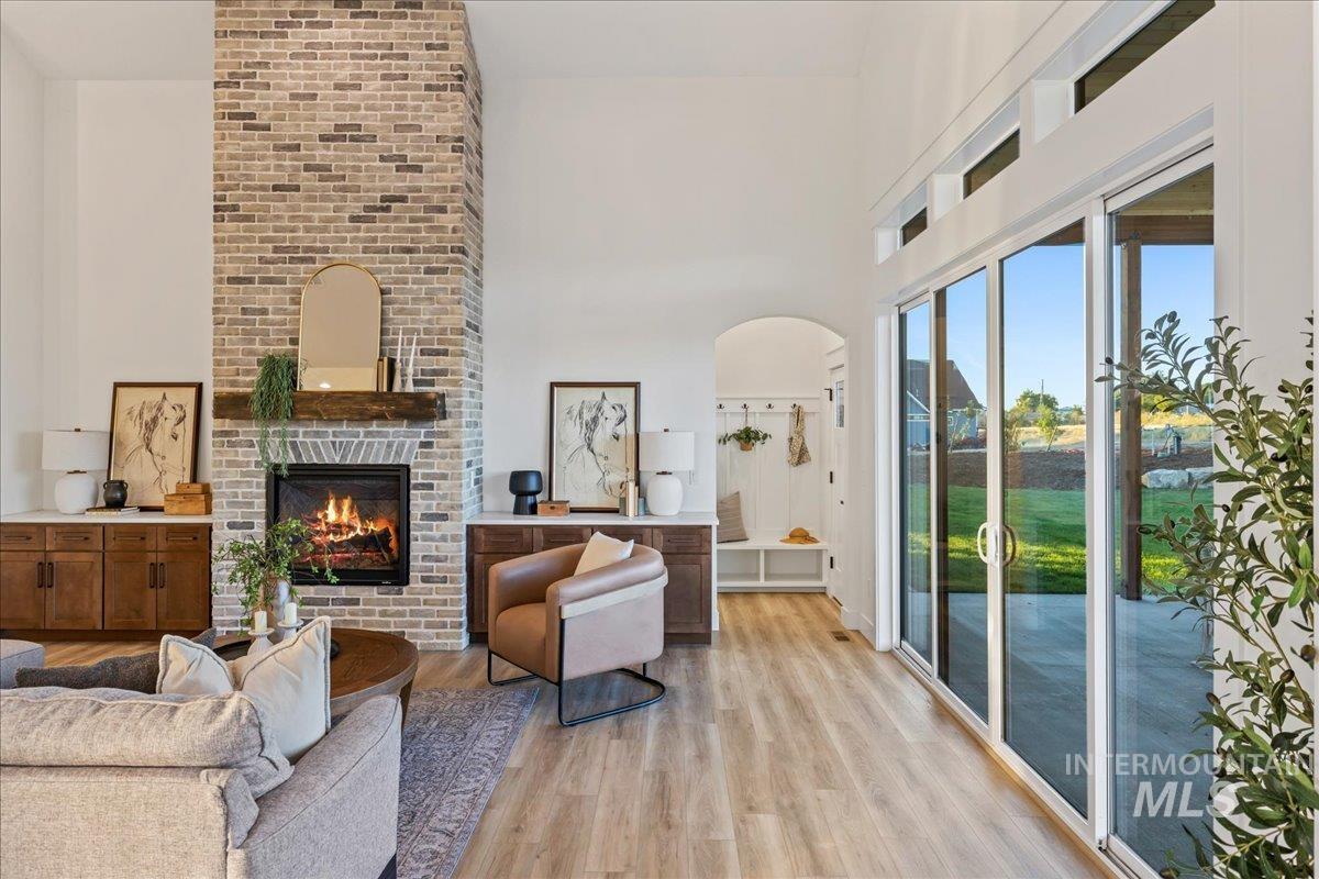 Living area featuring wood finished floors, a fireplace, arched walkways, and a high ceiling