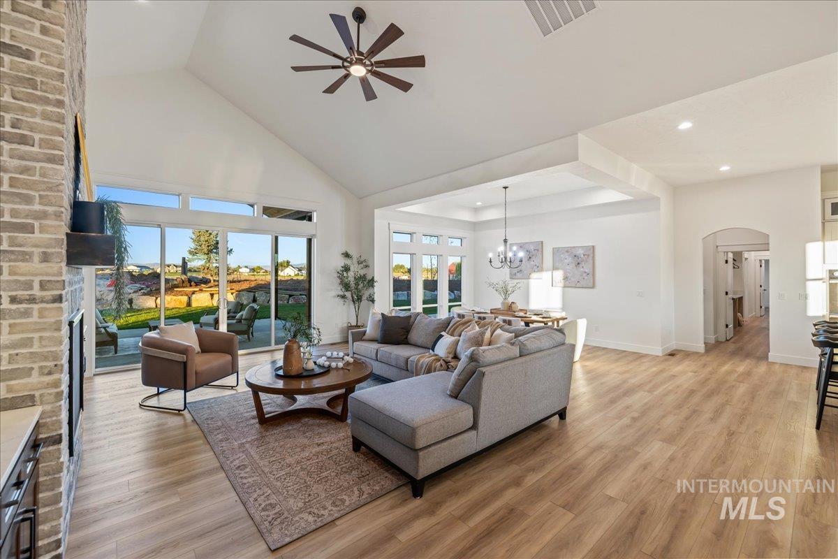 Living area featuring high vaulted ceiling, light wood-style floors, ceiling fan, arched walkways, and recessed lighting