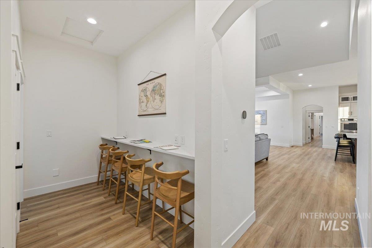 Bar area featuring light wood-type flooring, recessed lighting, arched walkways, oven, and light countertops