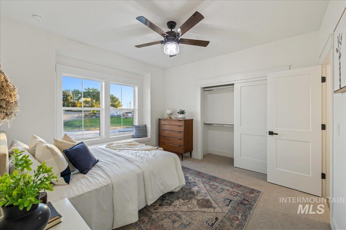 Bedroom with light colored carpet, ceiling fan, and a closet