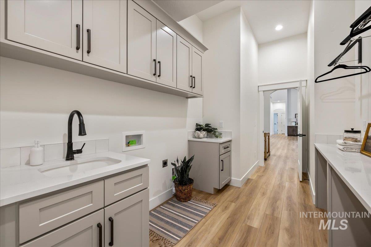 Washroom featuring light wood-style flooring, washer hookup, cabinet space, electric dryer hookup, and a towering ceiling
