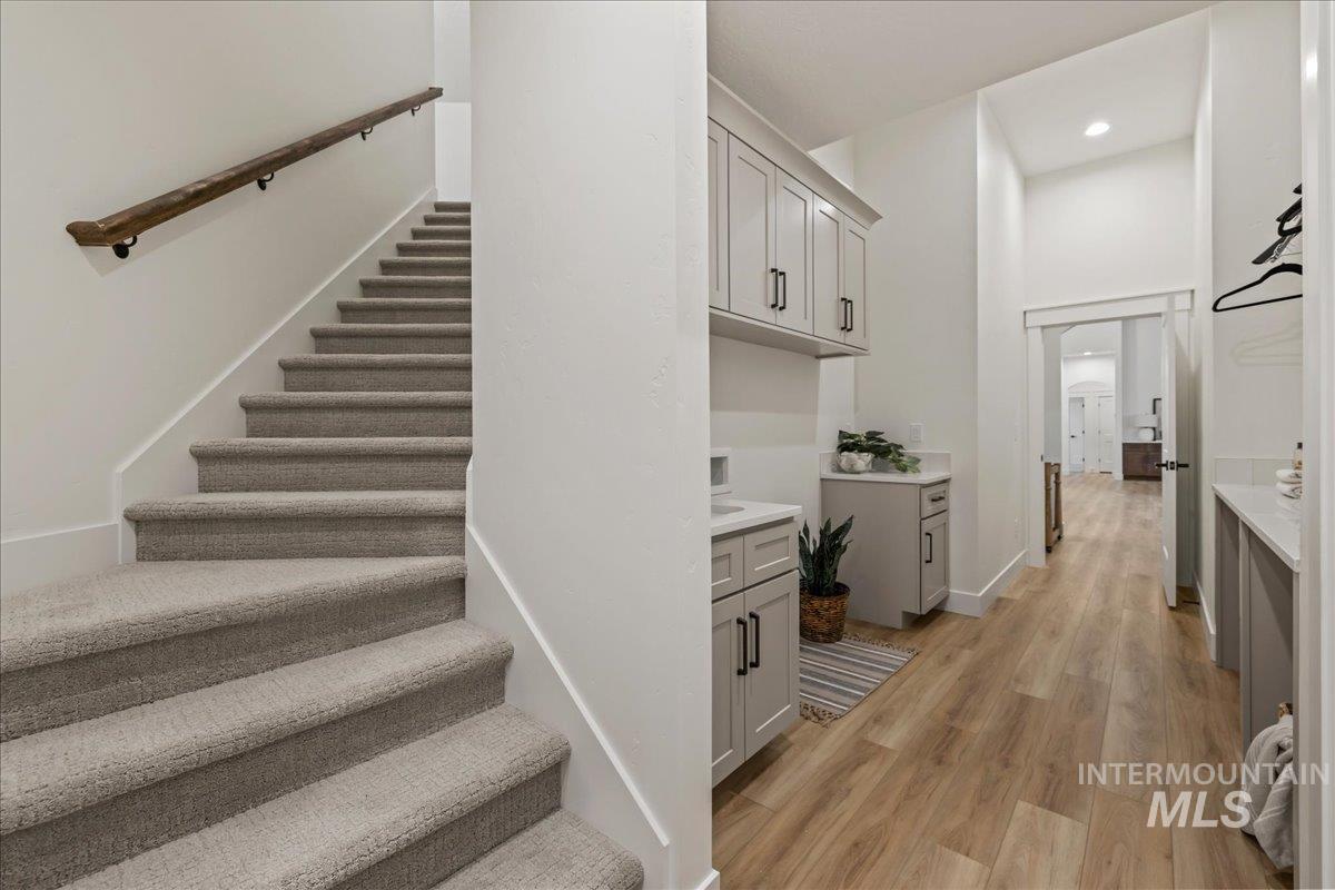 Staircase with wood finished floors and recessed lighting